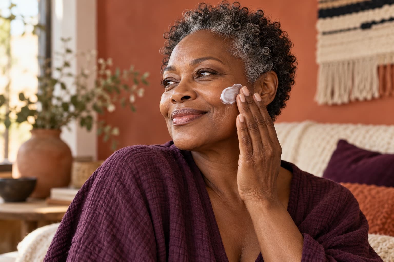 Femme noire aux cheveux naturellement grisonnants appliquant une crème